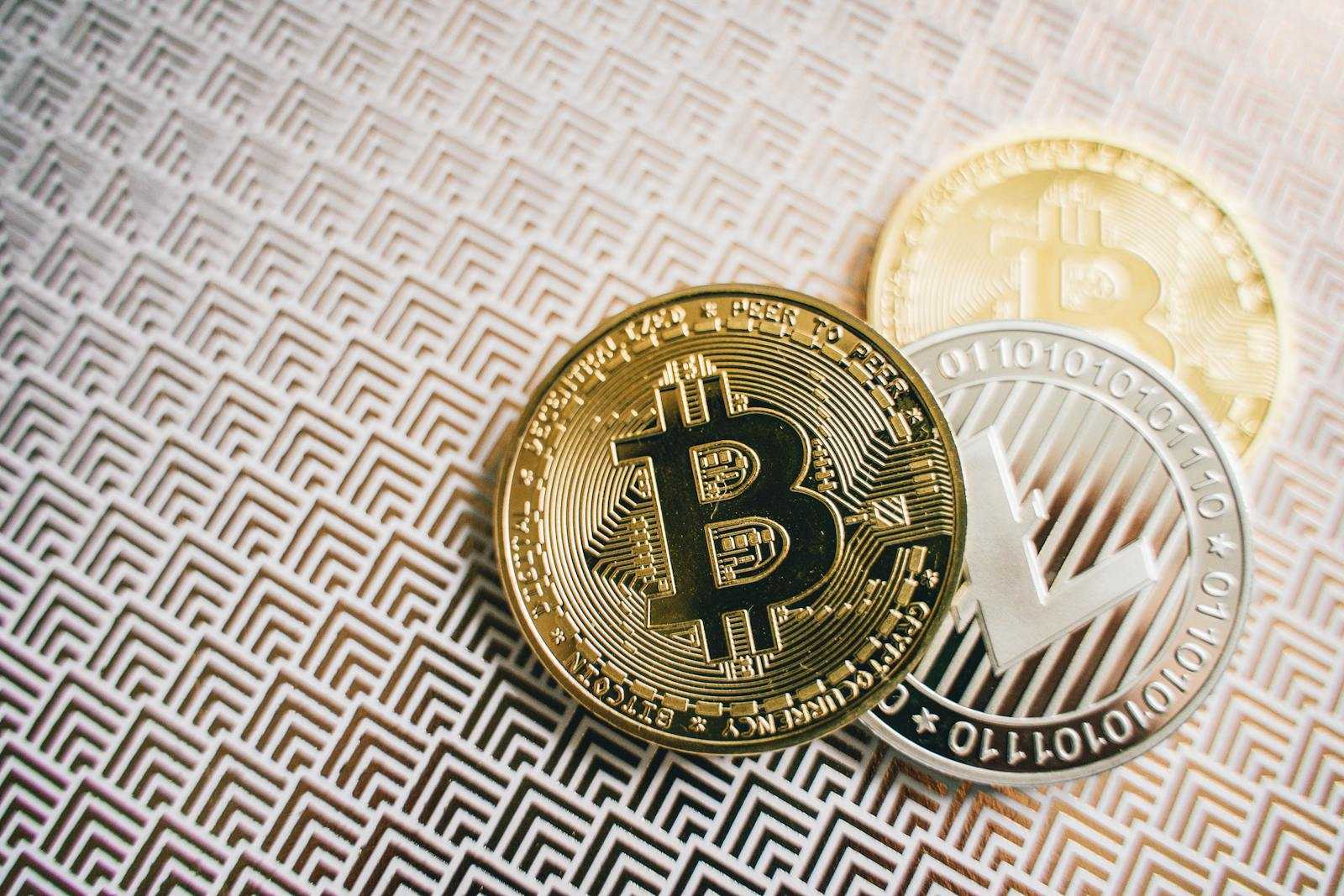 A close-up image of Bitcoin and Litecoin coins placed on an intricate geometric pattern, emphasizing cryptocurrency and economy.