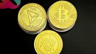 three gold bitcoins sitting on top of a black table