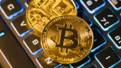 Two Bitcoin coins resting on an illuminated keyboard, showing cryptocurrency and digital finance themes.