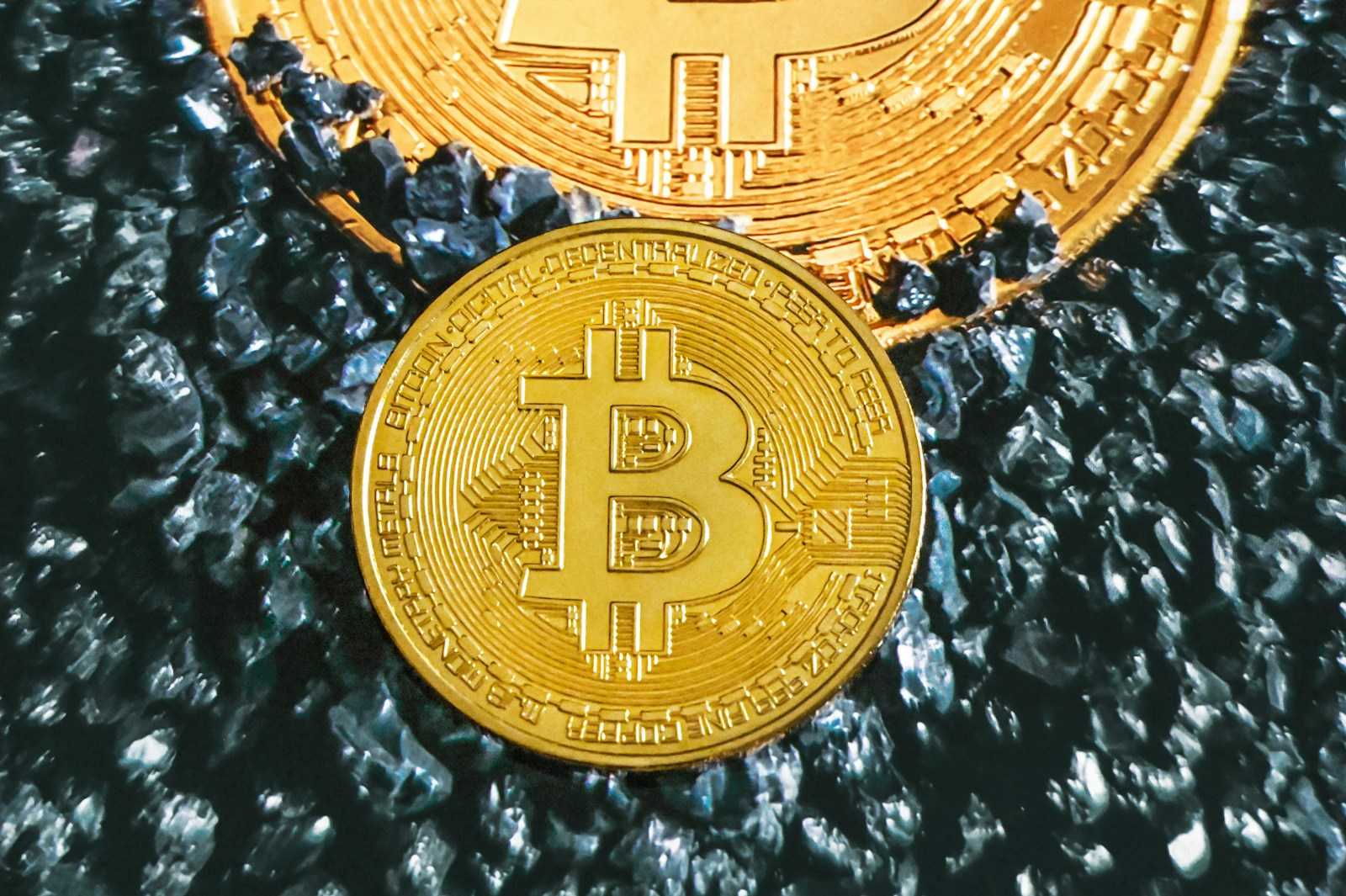 two gold bitcoins sitting on top of each other