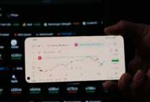 A person holding a business card in front of a computer screen